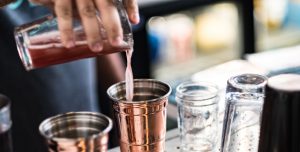 A bartender pours a custom made concoction into a copper cup